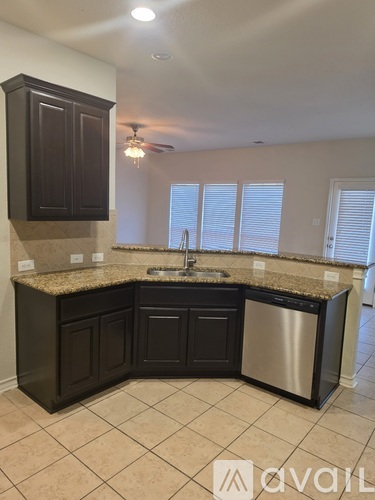 A kitchen with dark brown cabinets and granite countertops.