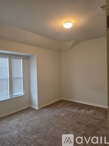 A room with a carpeted floor and a window with blinds.
