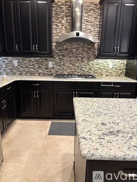 A kitchen with black cabinets and a granite countertop.