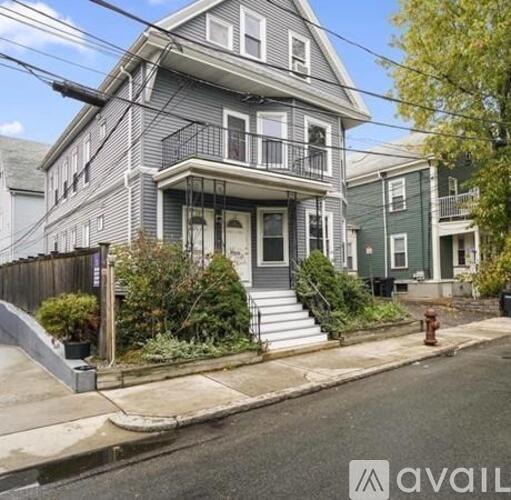 A grey house with a balcony and a fire hydrant in front.