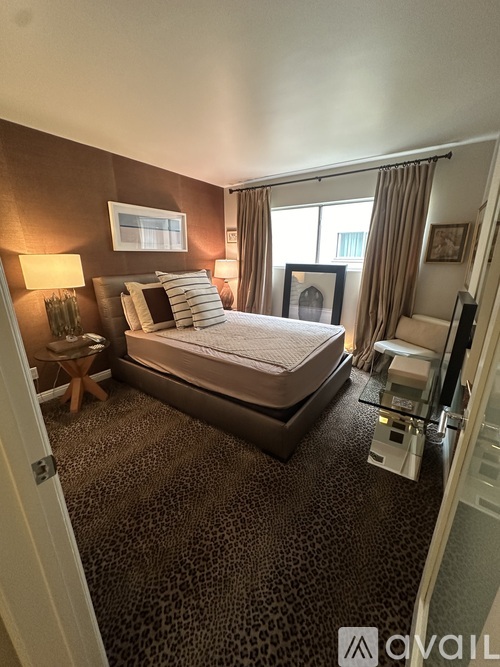 A bedroom with a large bed and a leopard print carpet.