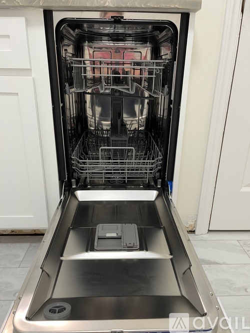 A dishwasher is open, showing the bottom rack and the dishes inside.