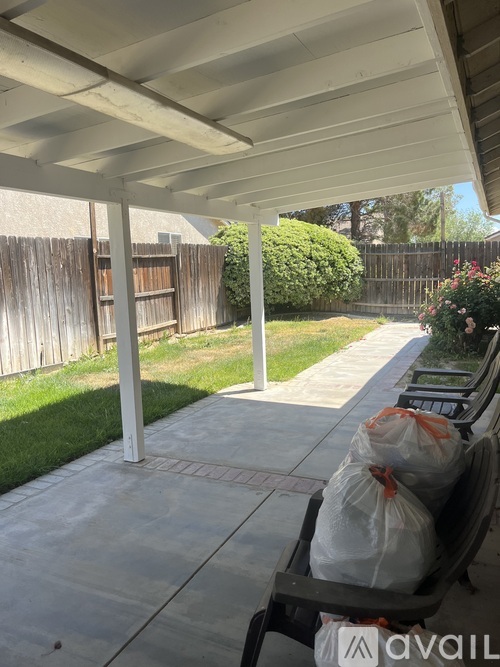 A patio with a white roof and a bench with two bags on it.