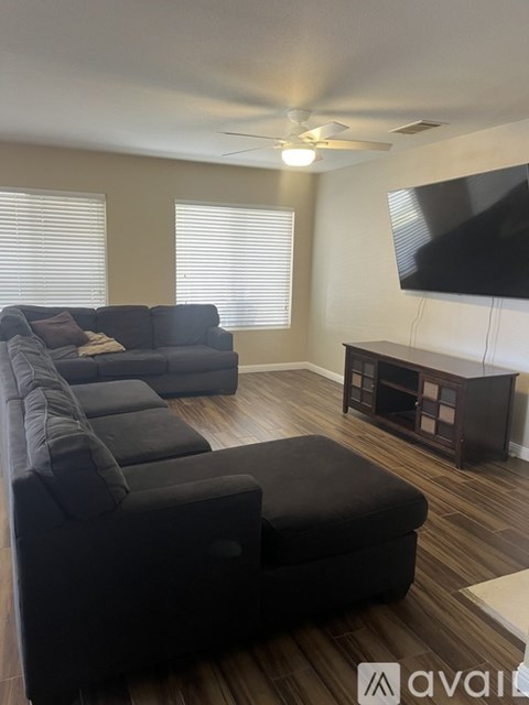 A living room with a black couch and a television mounted on the wall.