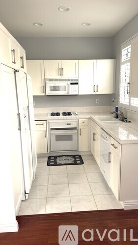 A kitchen with white cabinets and appliances.