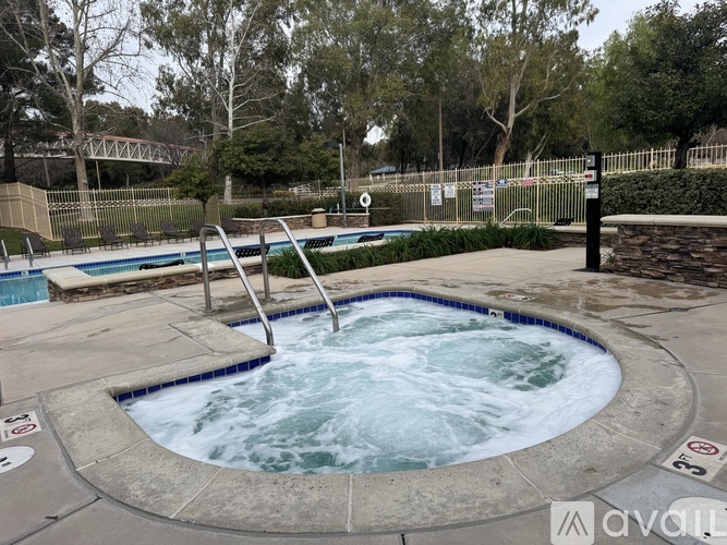 A hot tub in the middle of a pool surrounded by trees.