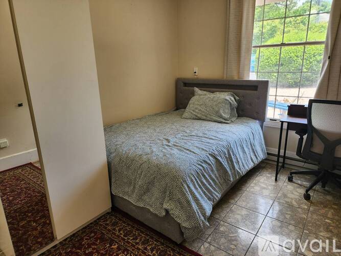 A bedroom with a bed, chair, and window.