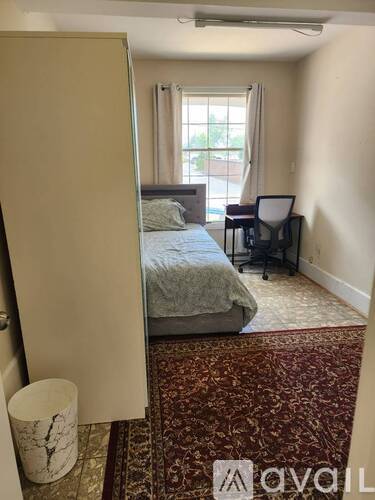 A bedroom with a bed, chair, and a rug.