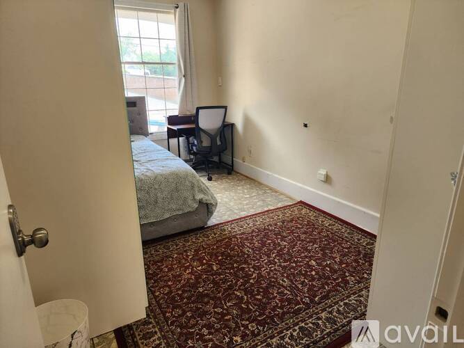 A room with a bed, a chair, and a rug.