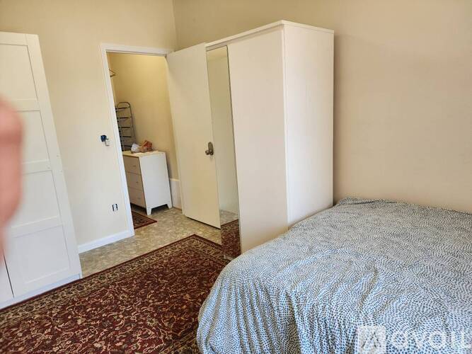 A bedroom with a bed, a wardrobe, and a small kitchenette.