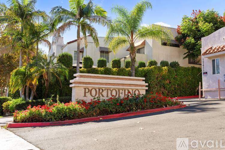 A sign that says "Portofino" is in front of a building with a red flower bed.