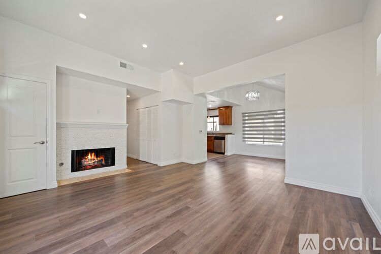 A spacious living room with a fireplace and wooden floors.