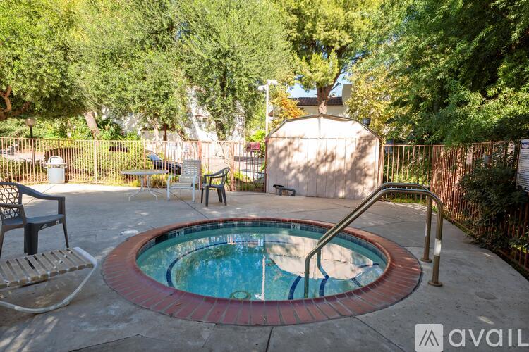 A small round pool surrounded by a fence and trees.