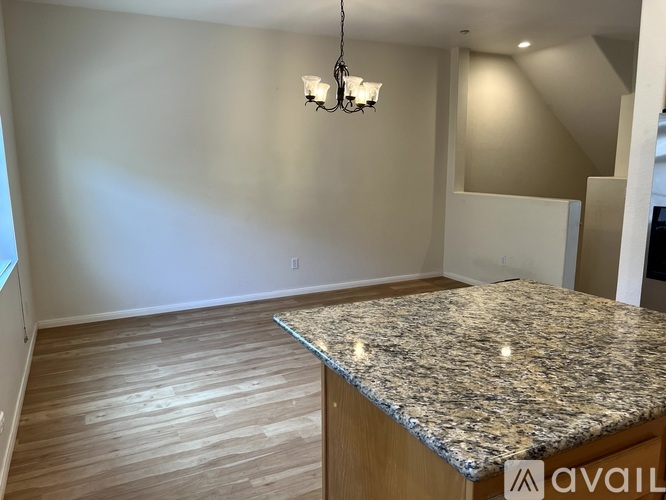 A room with a granite countertop and wooden flooring.