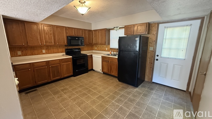 A kitchen with wooden cabinets and a black refrigerator.