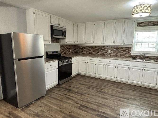 A kitchen with white cabinets and a stainless steel refrigerator.