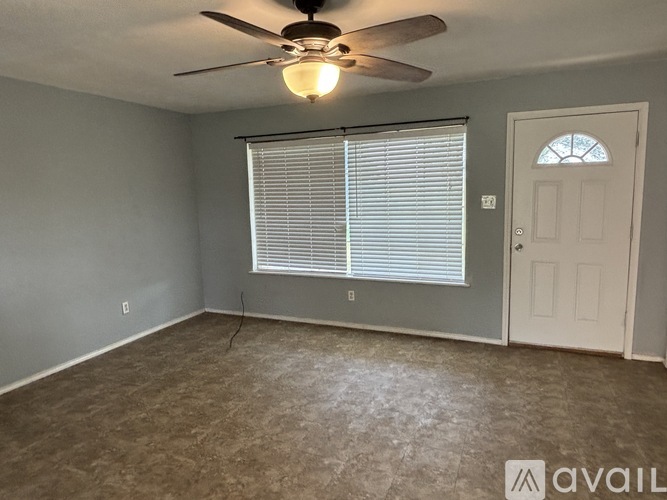 A room with a ceiling fan and a window with blinds.