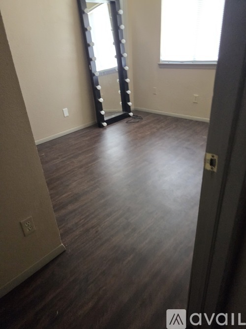 A room with wooden flooring and a large mirror on the wall.