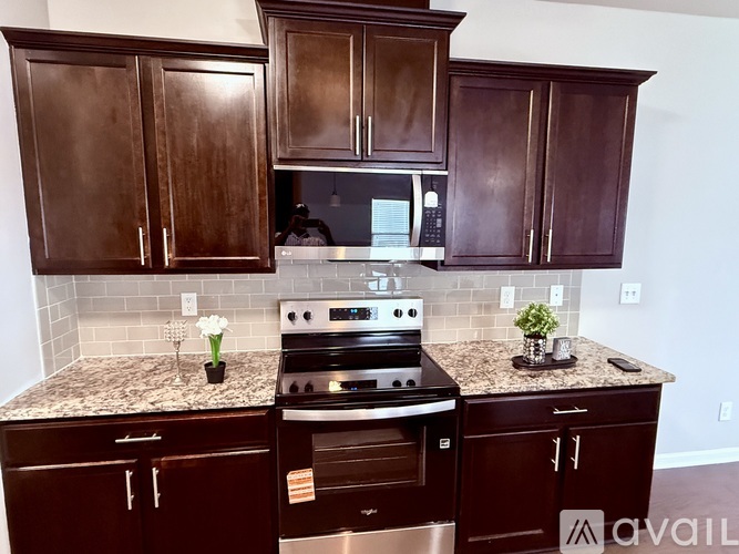 A kitchen with dark brown cabinets and granite countertops.