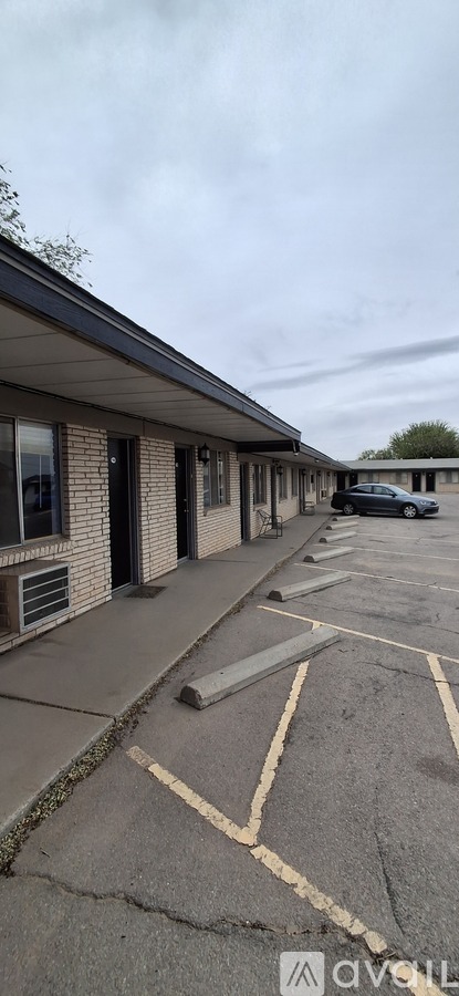 A parking lot with a car parked and a building in the background.