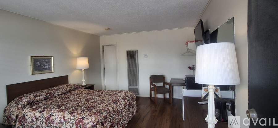 A bedroom with a large bed and a desk with a lamp.