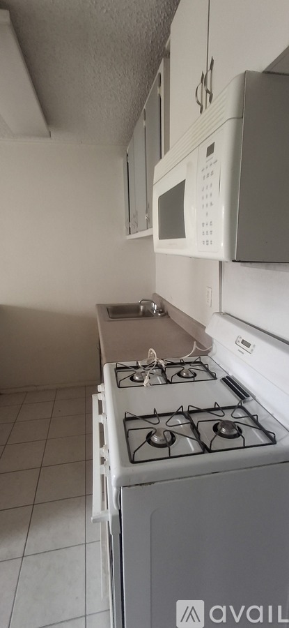 A white microwave oven is mounted above a white gas stove in a kitchen.