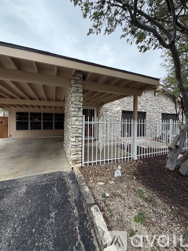 A stone building with a wooden roof and a white fence.