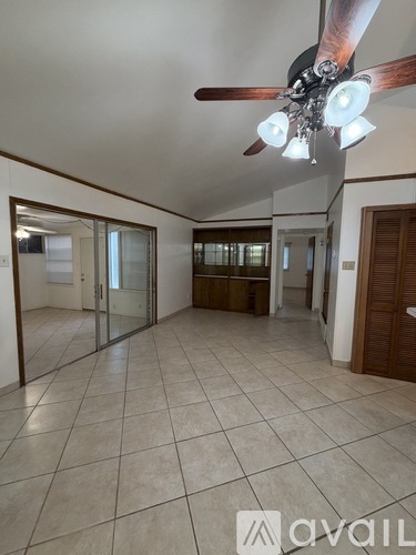 A spacious room with a ceiling fan and tiled flooring.