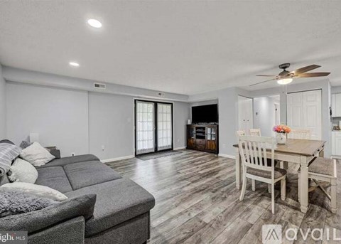 A spacious living room with a grey sofa and a wooden dining table.