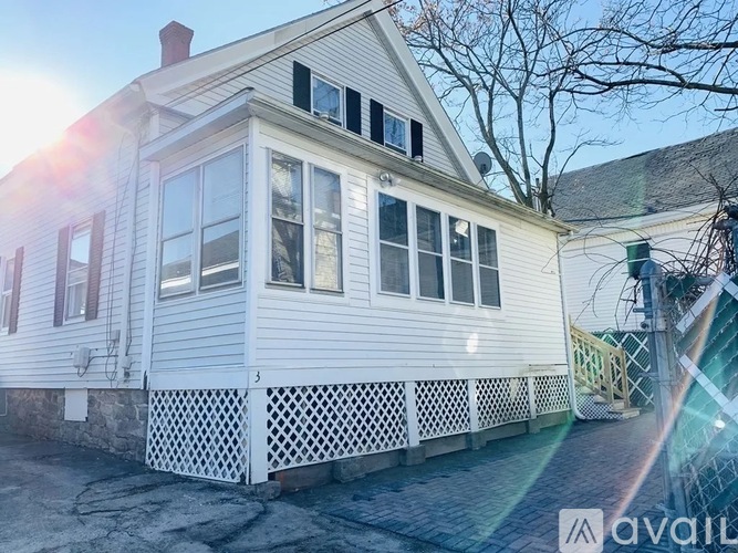 A house with a white exterior and a porch with a lattice design.