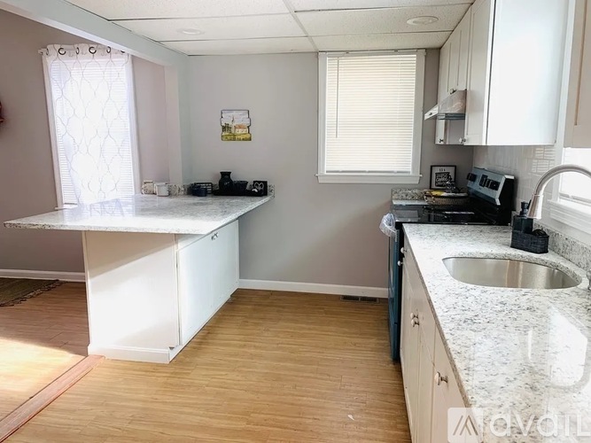 A kitchen with a white countertop and wooden flooring.