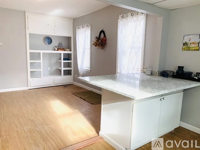 A kitchen with a white countertop and wooden flooring.