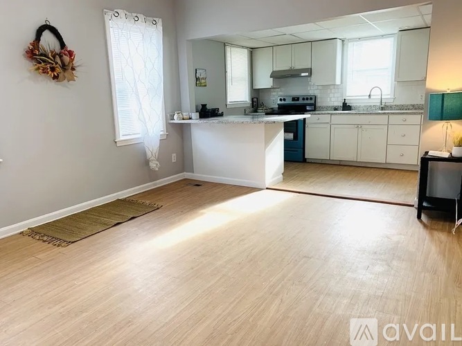 A kitchen with white cabinets and a wooden floor.