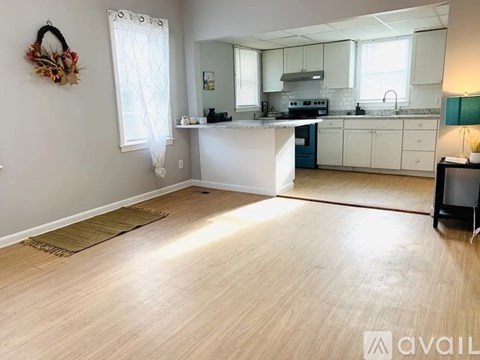 A kitchen with white cabinets and a wooden floor.