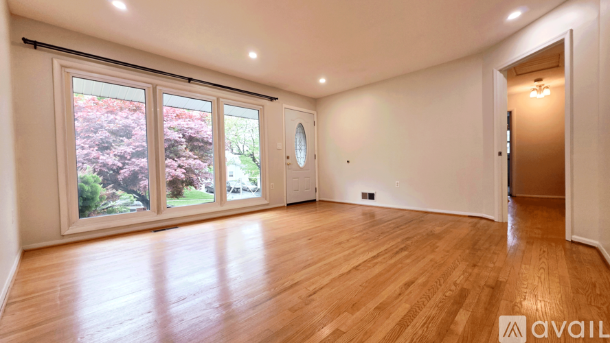 A room with wooden flooring and a large window overlooking a garden.