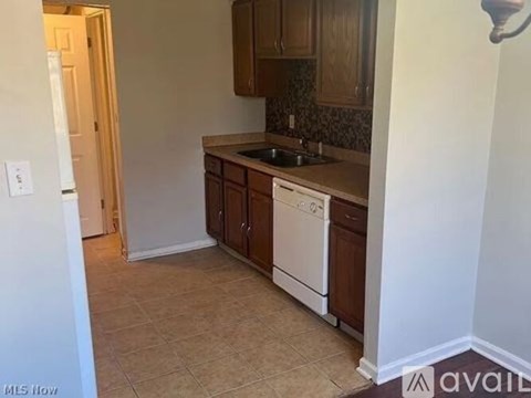 A kitchen with white appliances and brown cabinets.