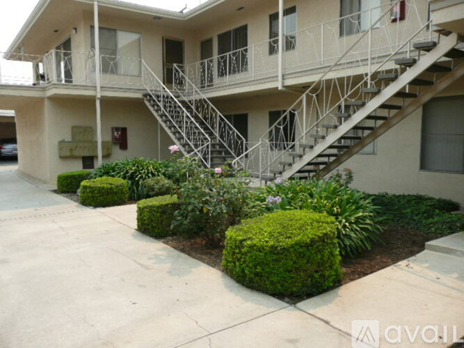 A building with a staircase and bushes in front.
