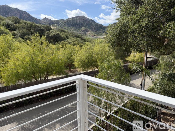 A balcony overlooks a valley with trees and mountains in the distance.