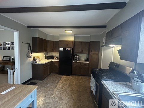 A kitchen with a black refrigerator and wooden cabinets.