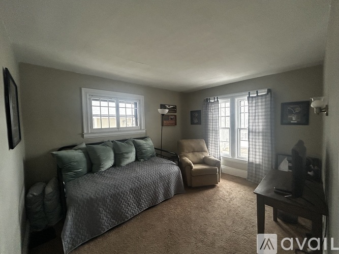 A bedroom with a bed, chair, and window.