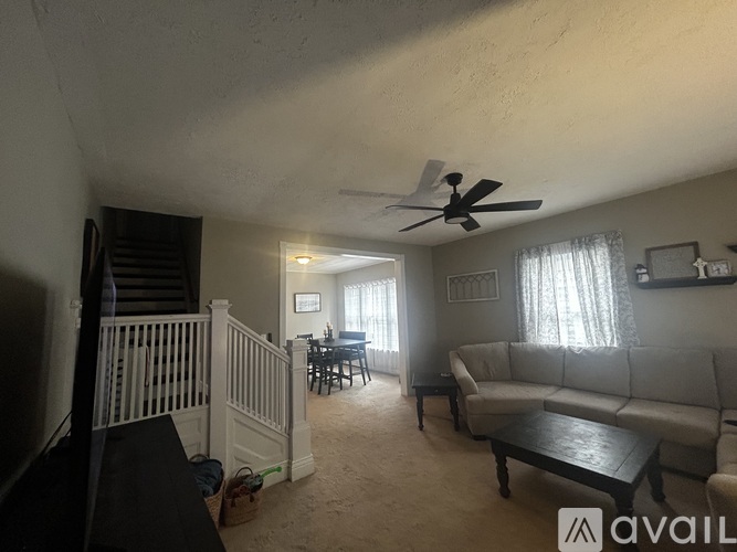 A living room with a couch, a dining table, and a ceiling fan.