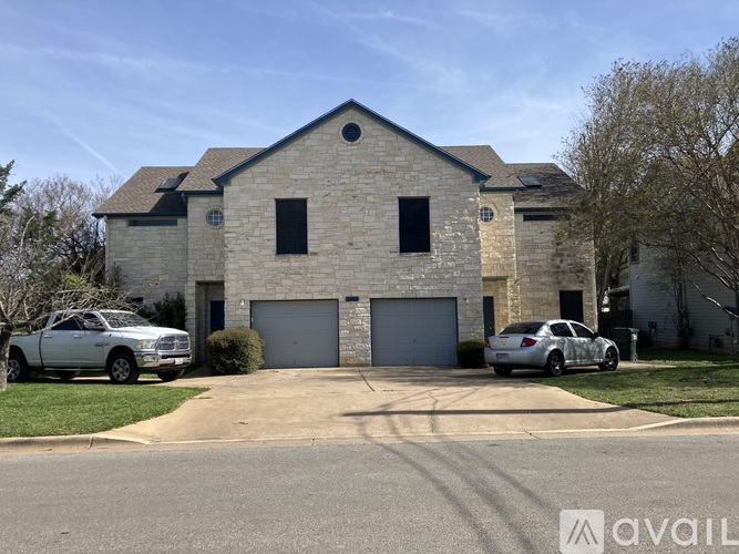 A house with a stone facade has a car parked in front of it.