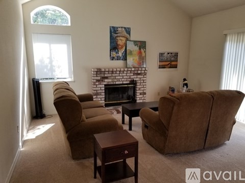 A living room with a fireplace and a painting of a woman on the wall.