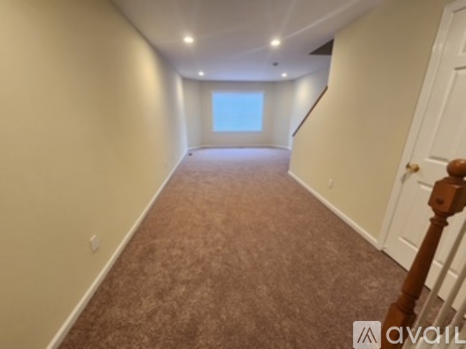 A long hallway with a carpeted floor and a door at the end.