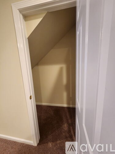 A white door is open to a room with beige walls.