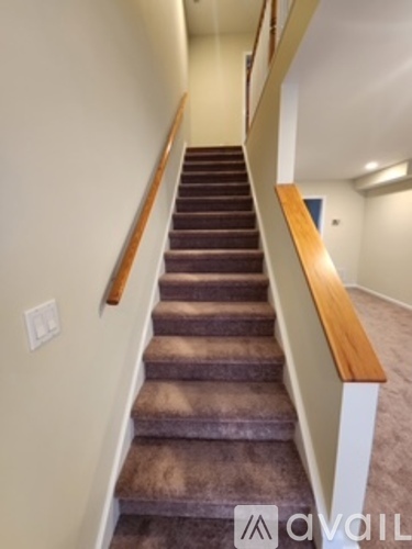 A staircase with a wooden handrail and beige walls.