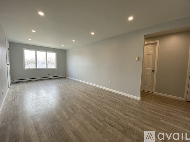 A spacious room with wooden flooring and a large window.