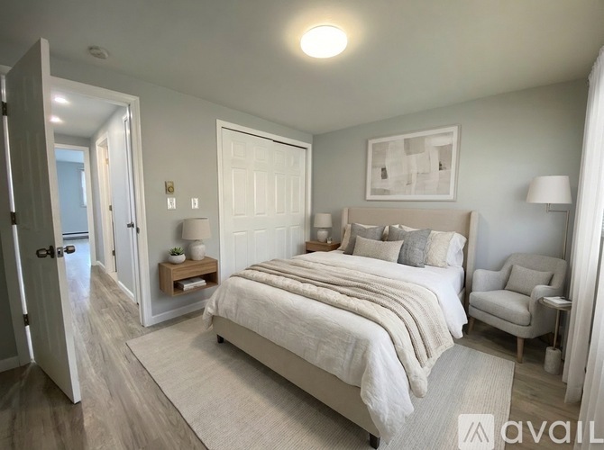A bedroom with a large bed, a chair, and a painting on the wall.