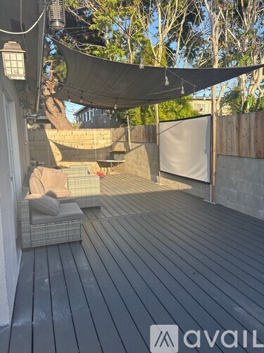 A wooden deck with a white couch and a black tarp covering the area.
