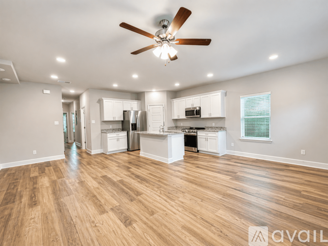 A spacious kitchen and living room with wooden floors and a ceiling fan.